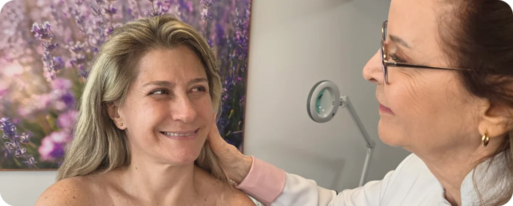 Atendimento de estética facial humanizada: especialista Sonia Reimberg avalia e cuida da pele de uma mulher madura.